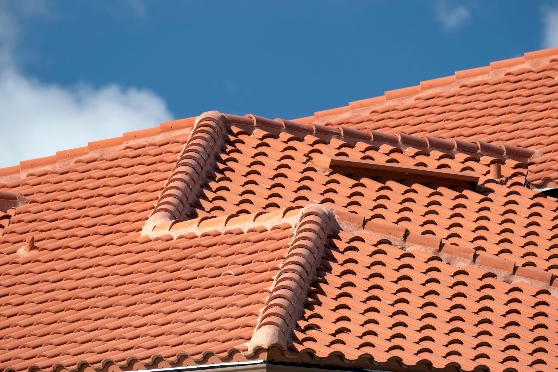 Terracotta roof tiles with ridges against a blue sky