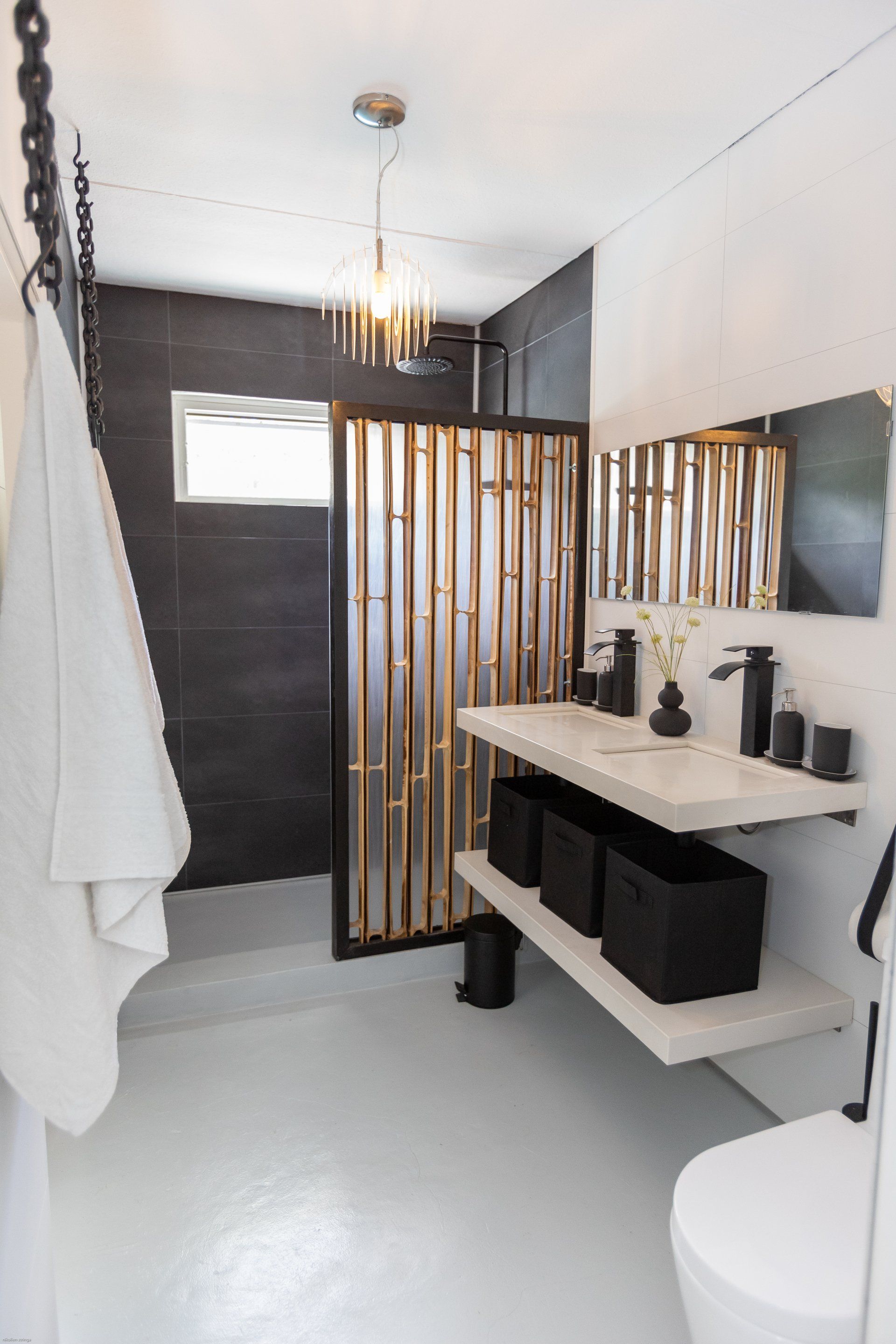 Moderne badkamer met een interieur in zwart, goud en wit. Voorzien van een douche, zwevend wastafelmeubel en toilet.