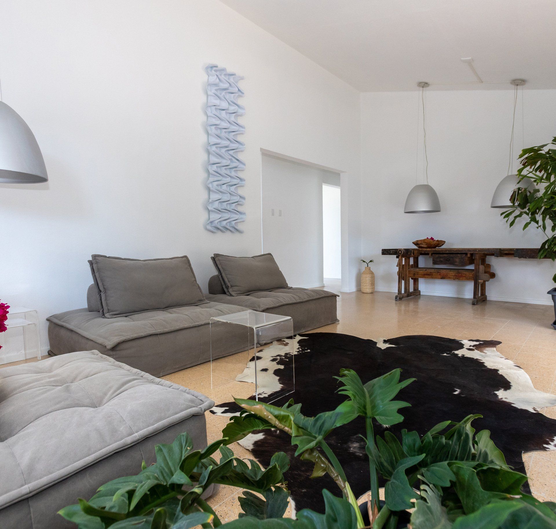 Een moderne woonkamer met grijze zitmeubelen, een houten tafel en een zwart-wit vloerkleed.