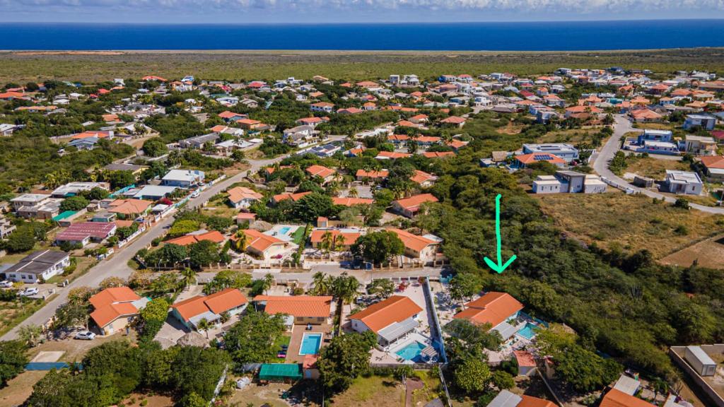 Luchtfoto van een kustplaats met huizen, zwembaden en weelderige groene vegetatie vlakbij de oceaan.