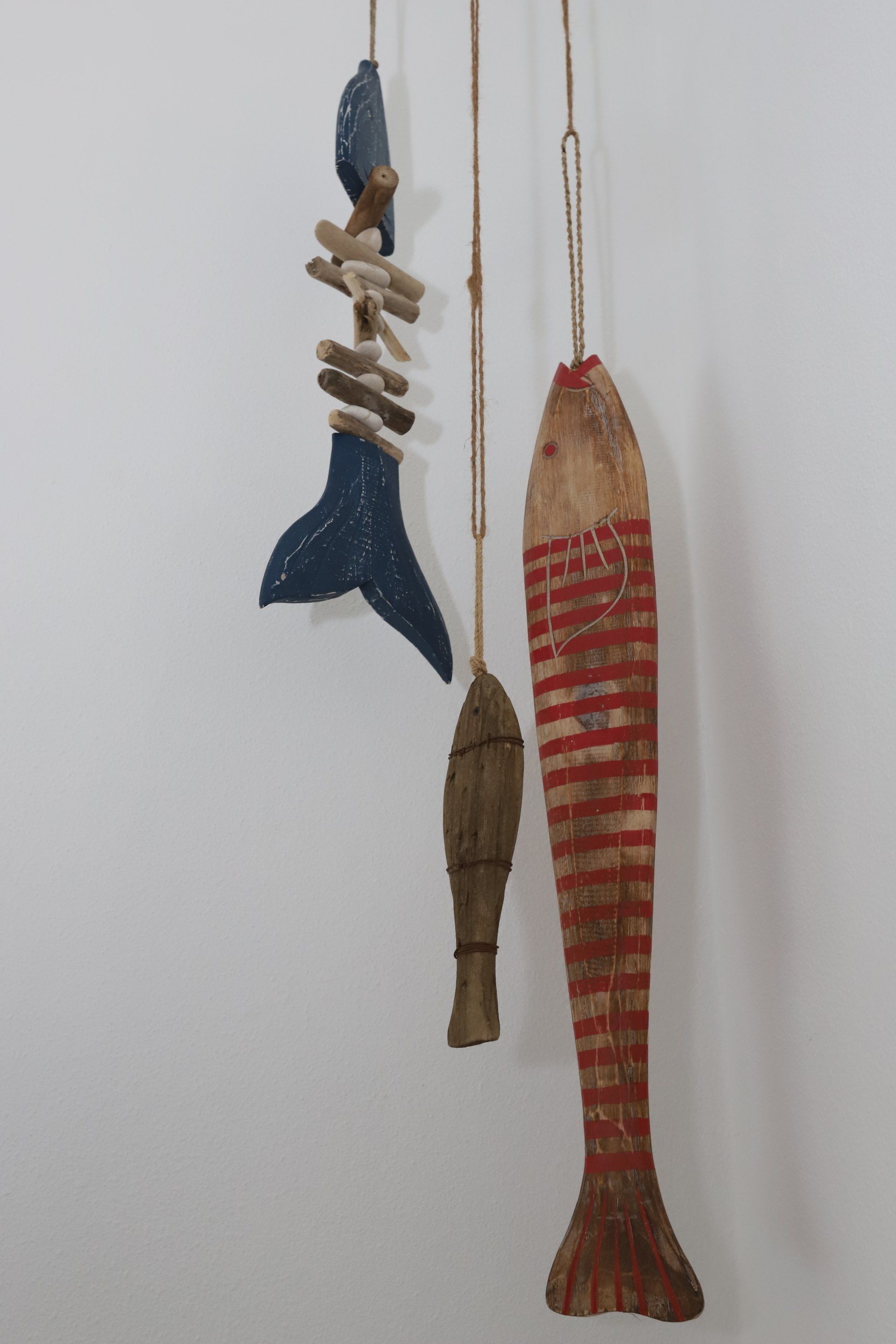 Hangende mobiel van drijfhout en houten vissen; in de kleuren blauw, rood en bruin.