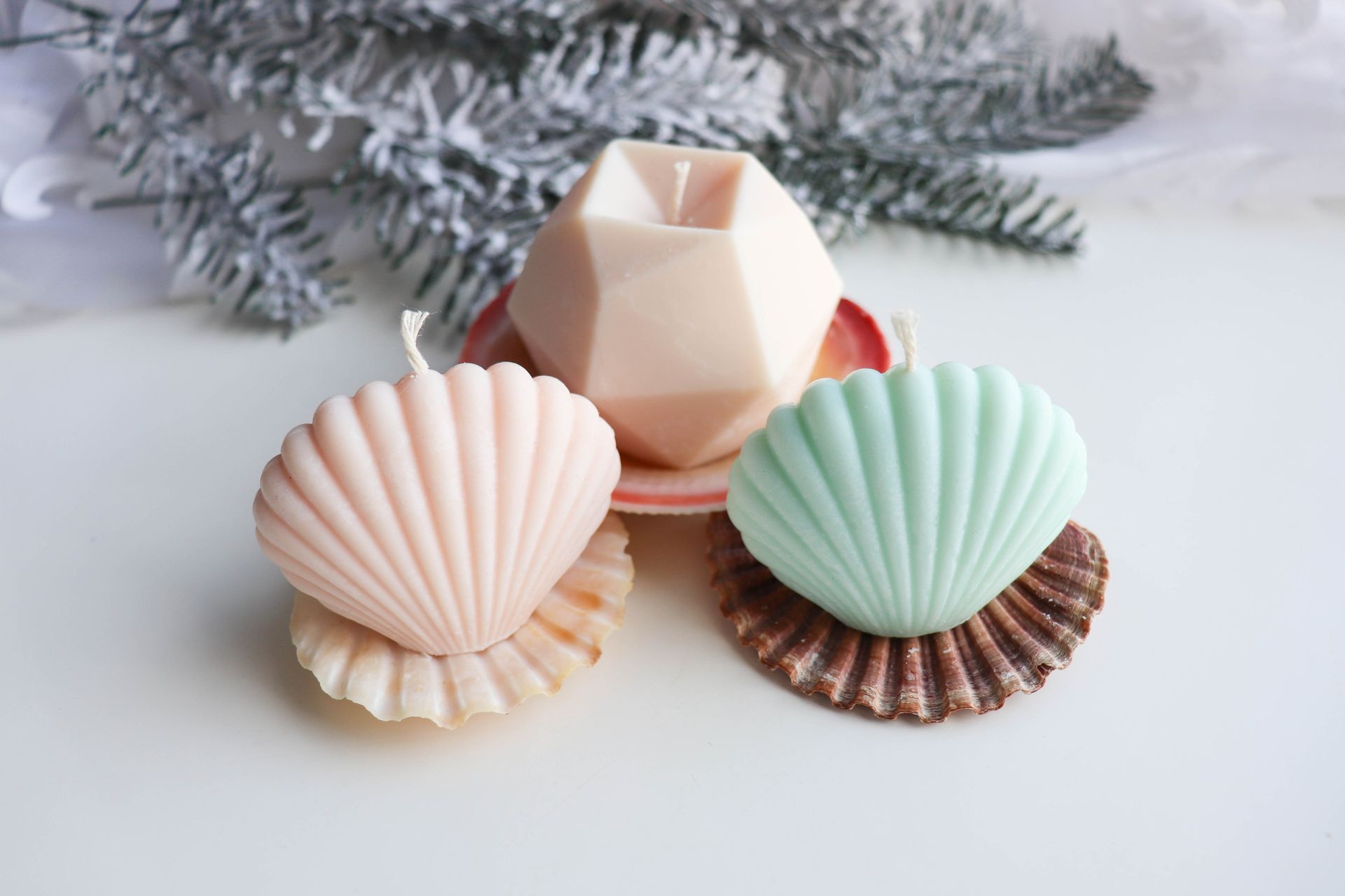 Three candles in the shape of seashells are sitting on a table.