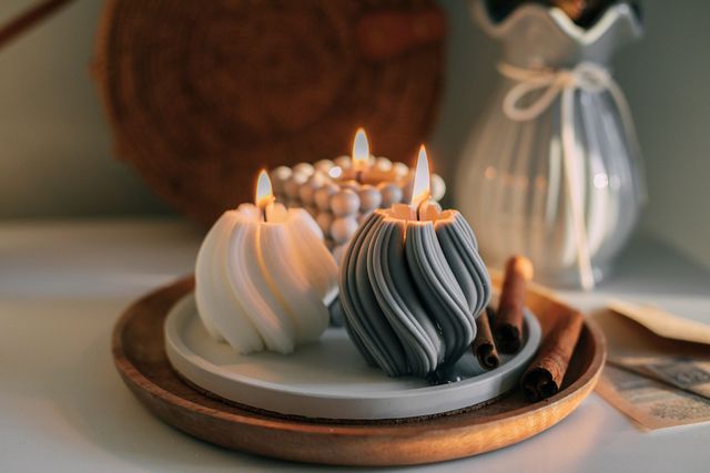 Three candles are sitting on a wooden tray on a table.