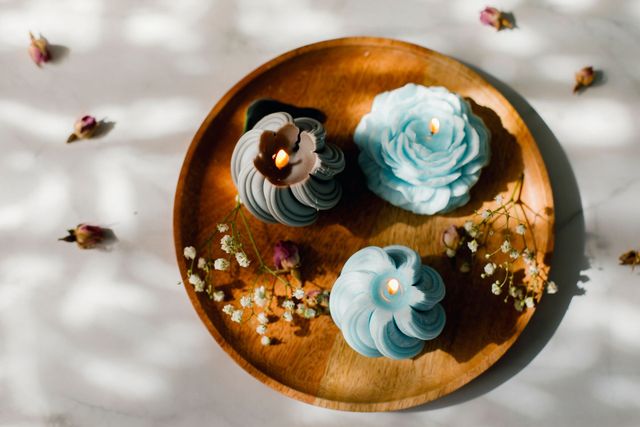 Three candles are on a wooden plate on a table.