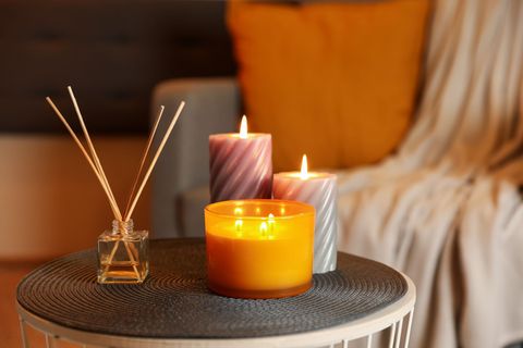 Candles and reed diffusers are on a table in a living room. Candles and reed diffusers are on a table in a living room.