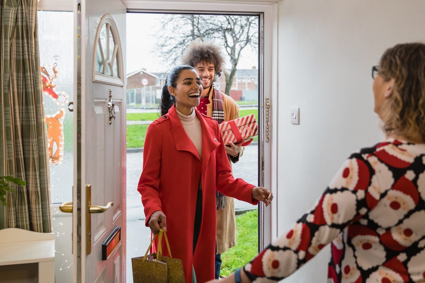 A woman in a red coat is standing in front of a door.