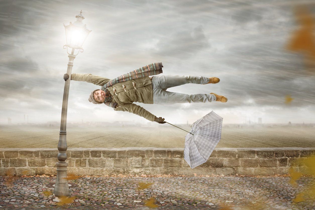A man is flying through the air while holding an umbrella.