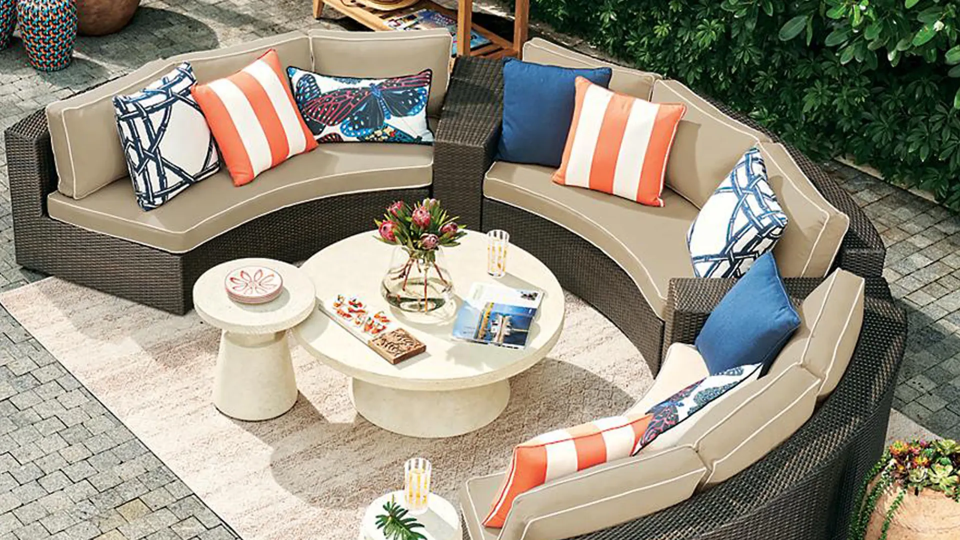 A round patio set with a couch , two tables , and a coffee table.