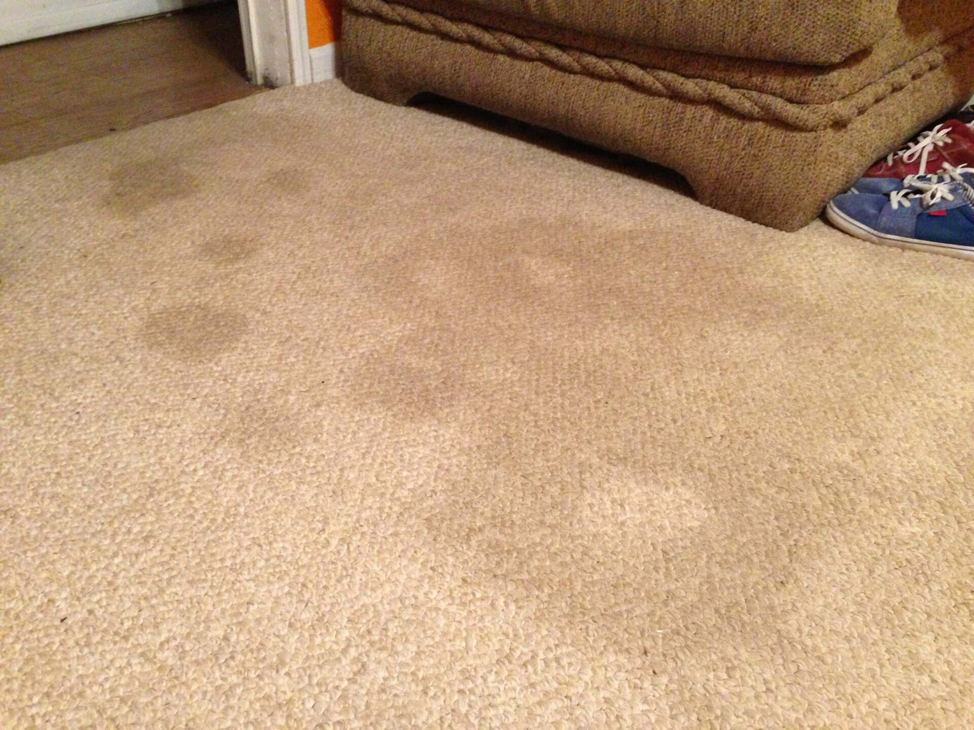 A dirty carpet next to a chair and a pair of shoes