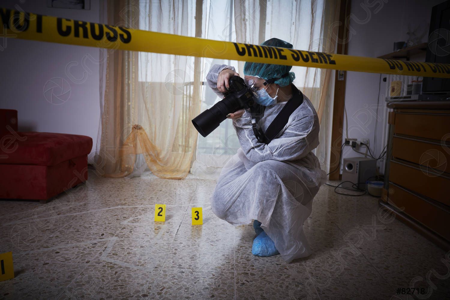 A forensic scientist is kneeling down in a living room taking a picture with a camera.