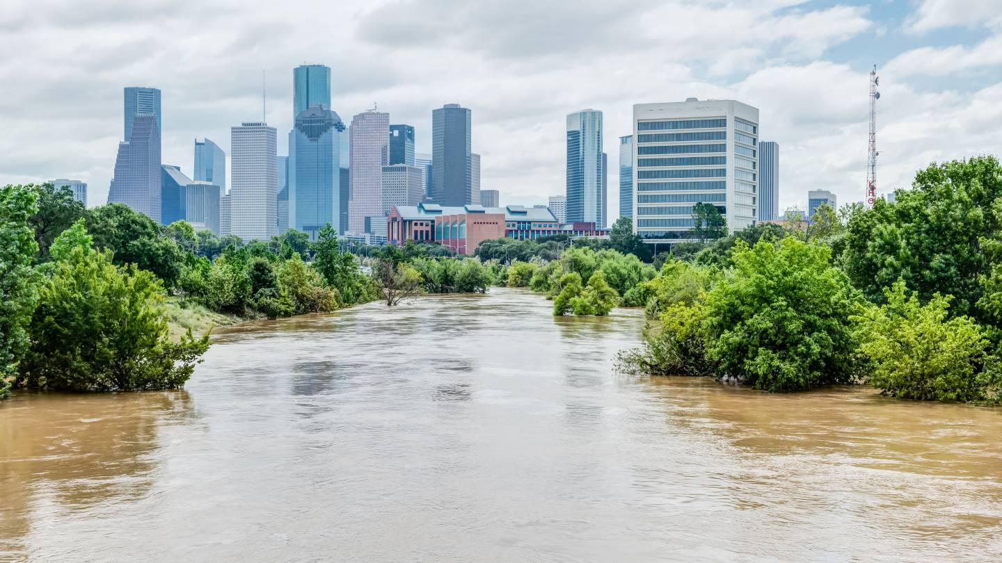 A flooded river with a city skyline in the background.