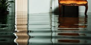 A chair is sitting on a flooded floor in a room.