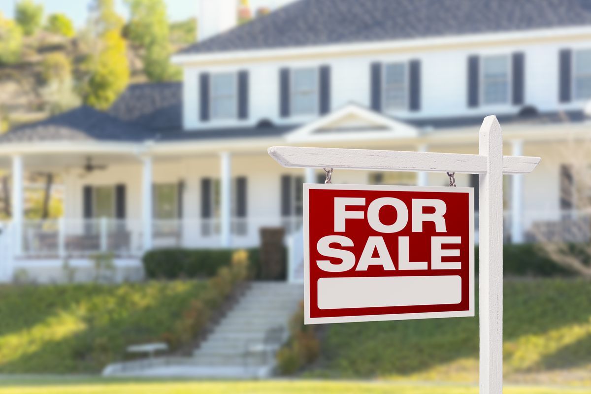 A for sale sign is in front of a house.