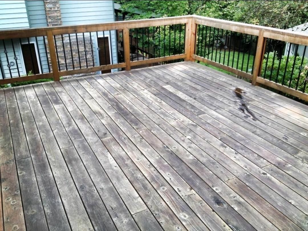 A wooden deck with a metal railing and a squirrel on it.