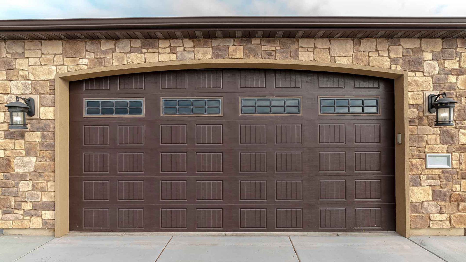 A large garage with double brown wooden doors after a garage door installation. A large garage with double brown wooden doors after a garage door installation.