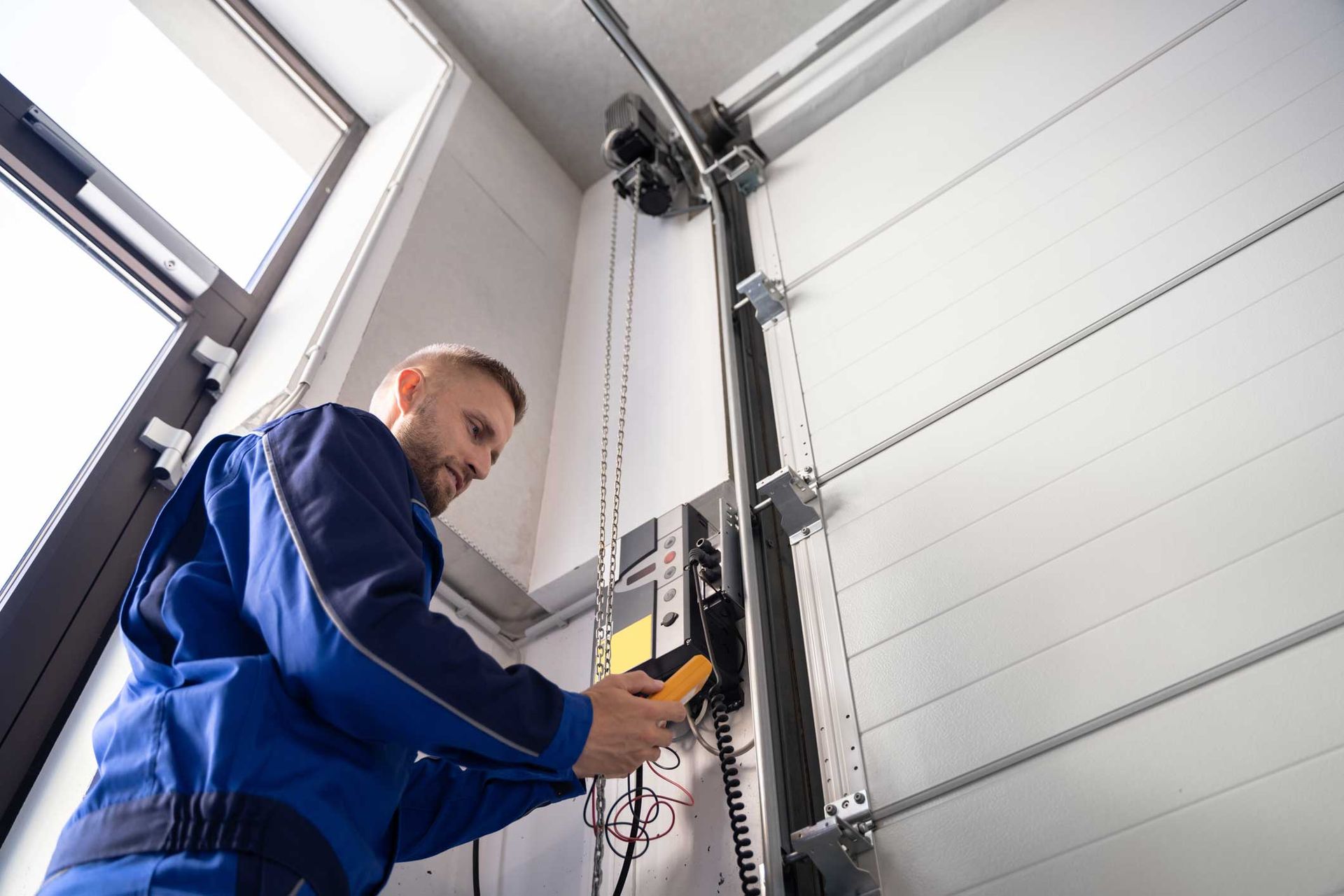 A uniformed garage door installer is performing a service.