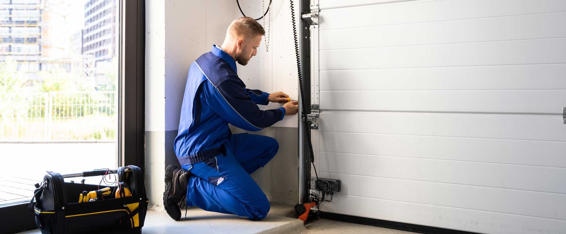 A uniformed garage door contractor is performing a garage door installation in a residential area. A uniformed garage door contractor is performing a garage door installation in a residential area.