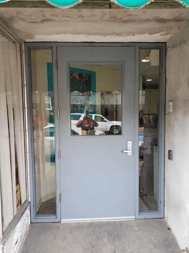 A person is taking a picture of their reflection in a glass door.
