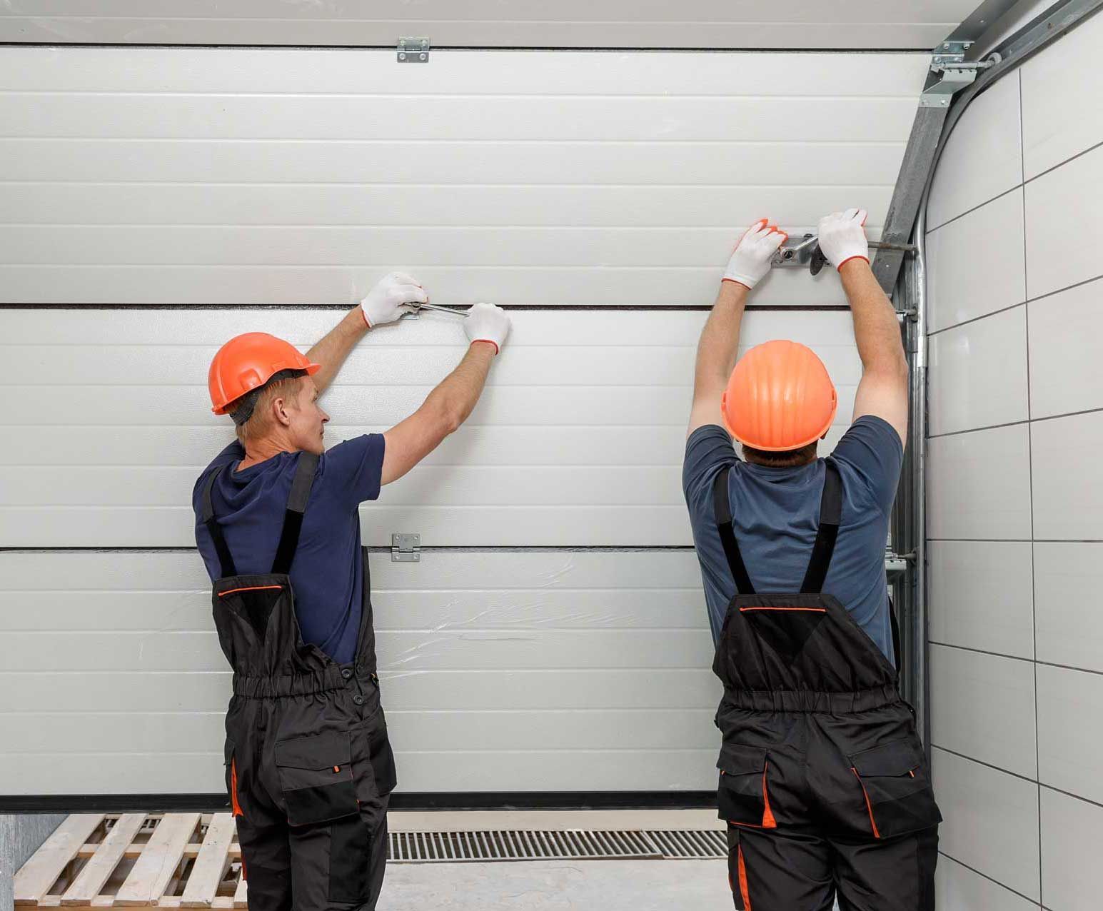 Two men are installing a garage door in a garage.