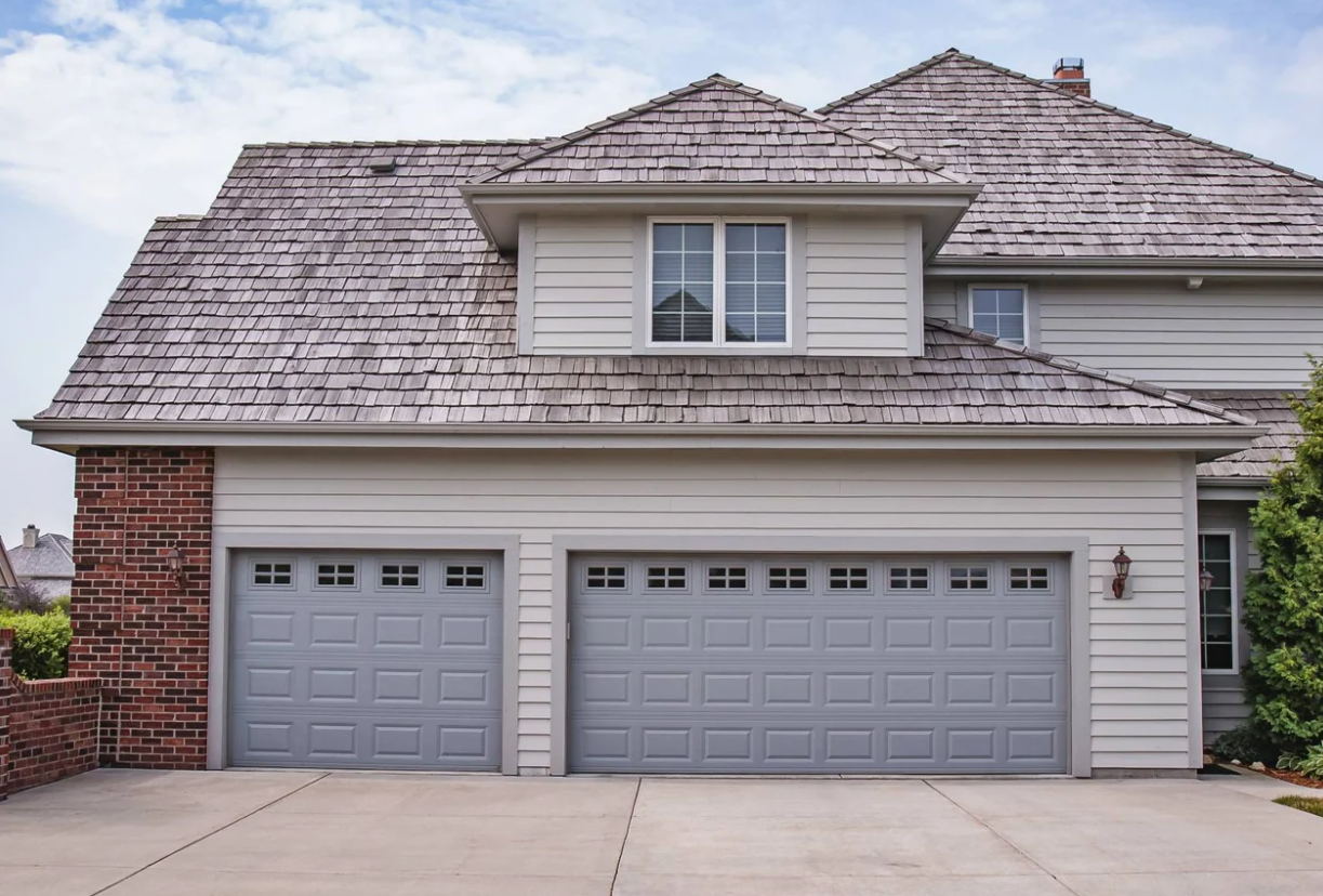 A black garage door is sitting in front of a brick house.