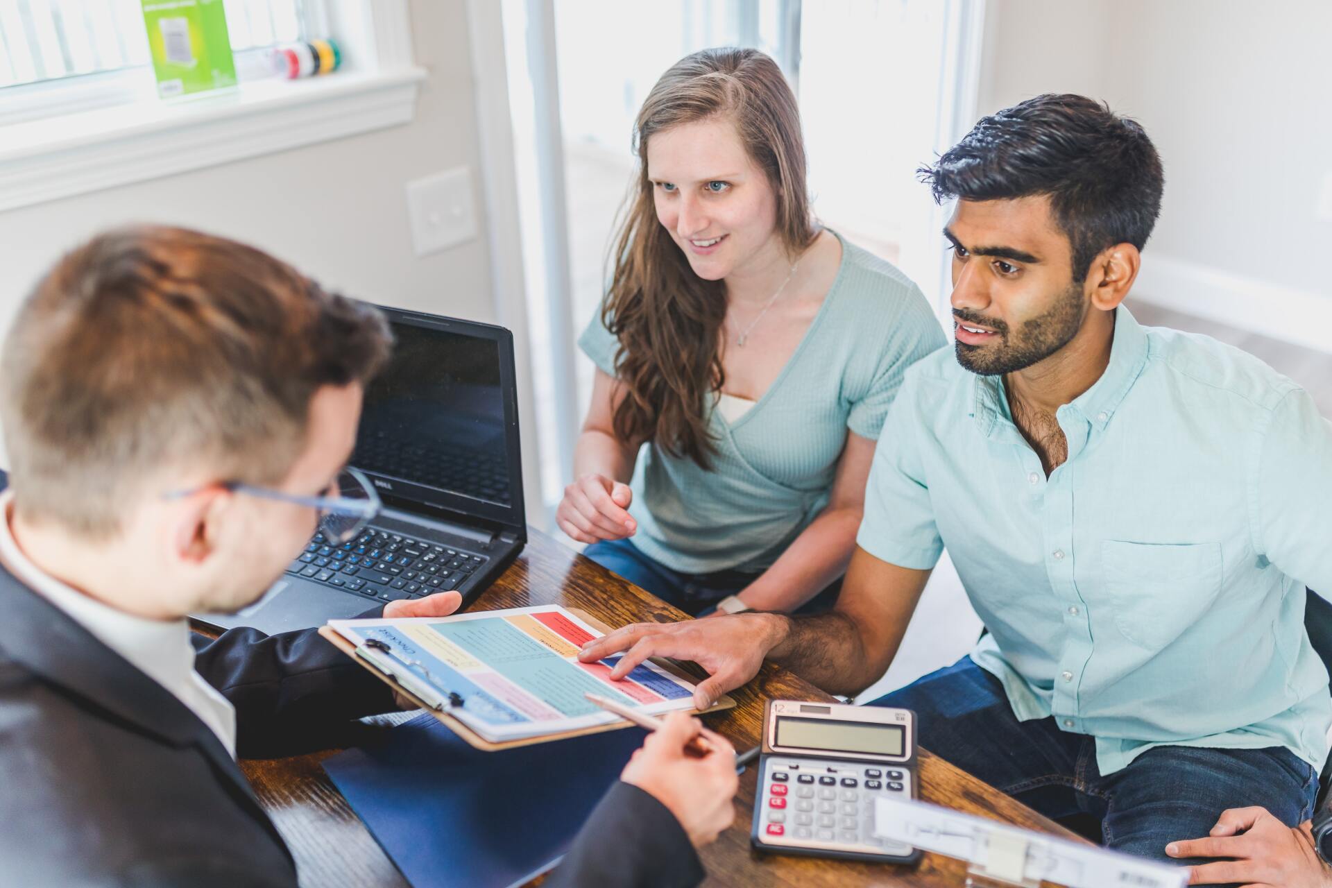 Young couple meeting with rent to own credit repair specialist looking at plan together