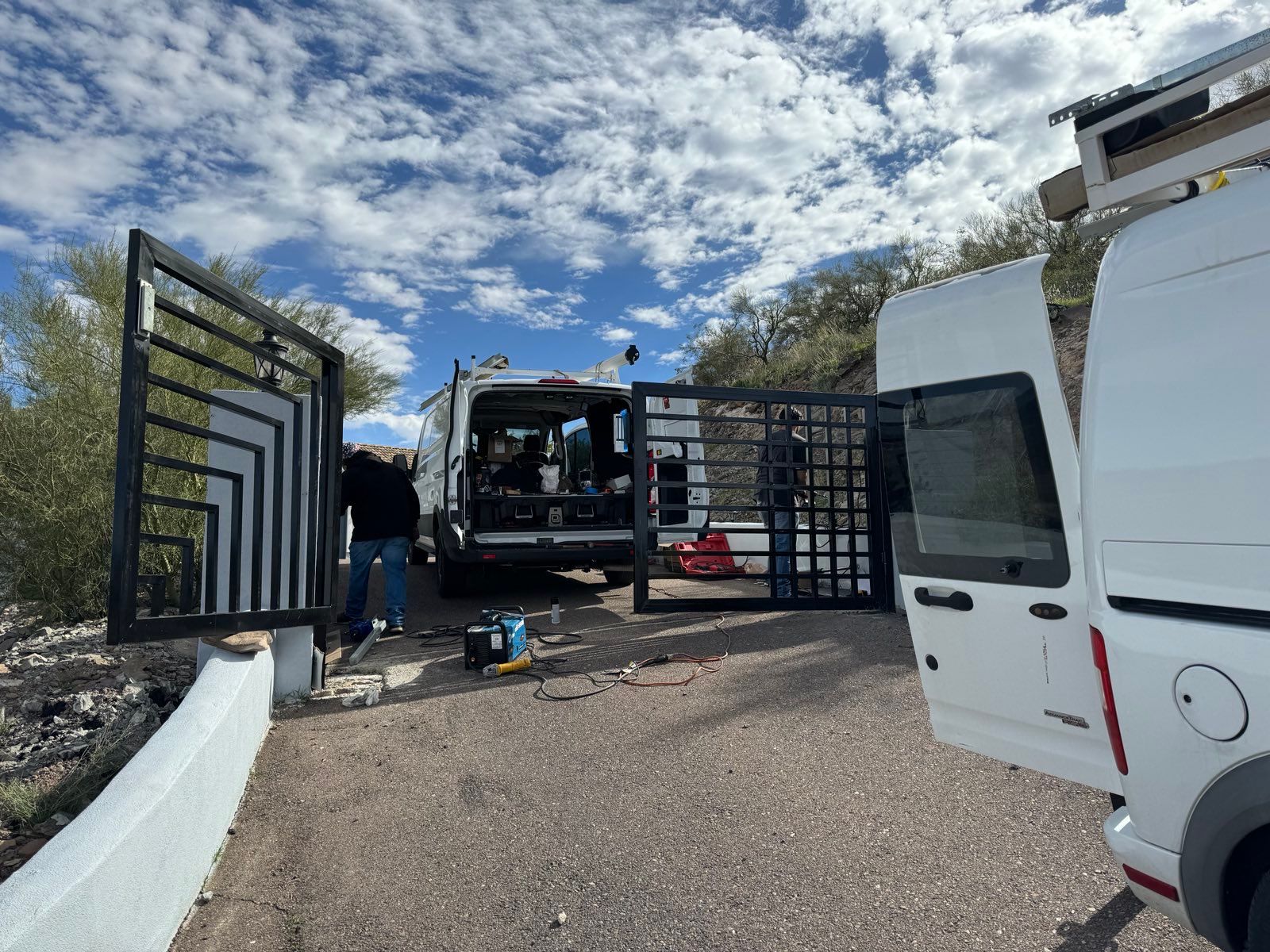 A man is working on a gate next to a white van.