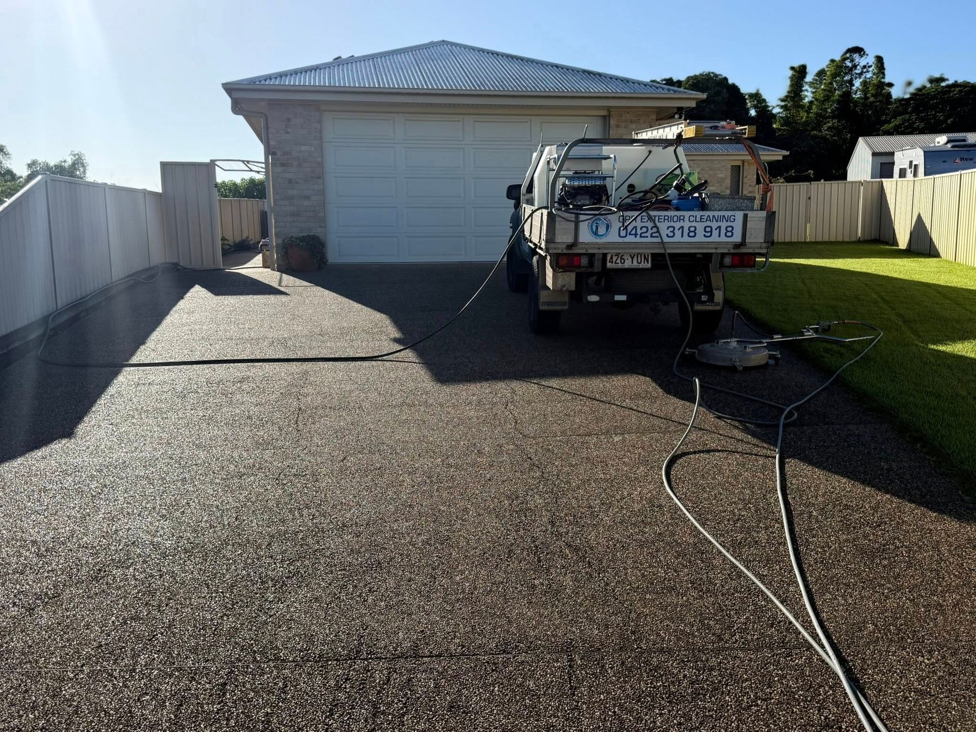 Truck With Ladder in a Driveway Beside a White Garage, With Gravel on the Left and Grass on the Right — CPR Exterior Cleaning in Svensson Heights, QLD