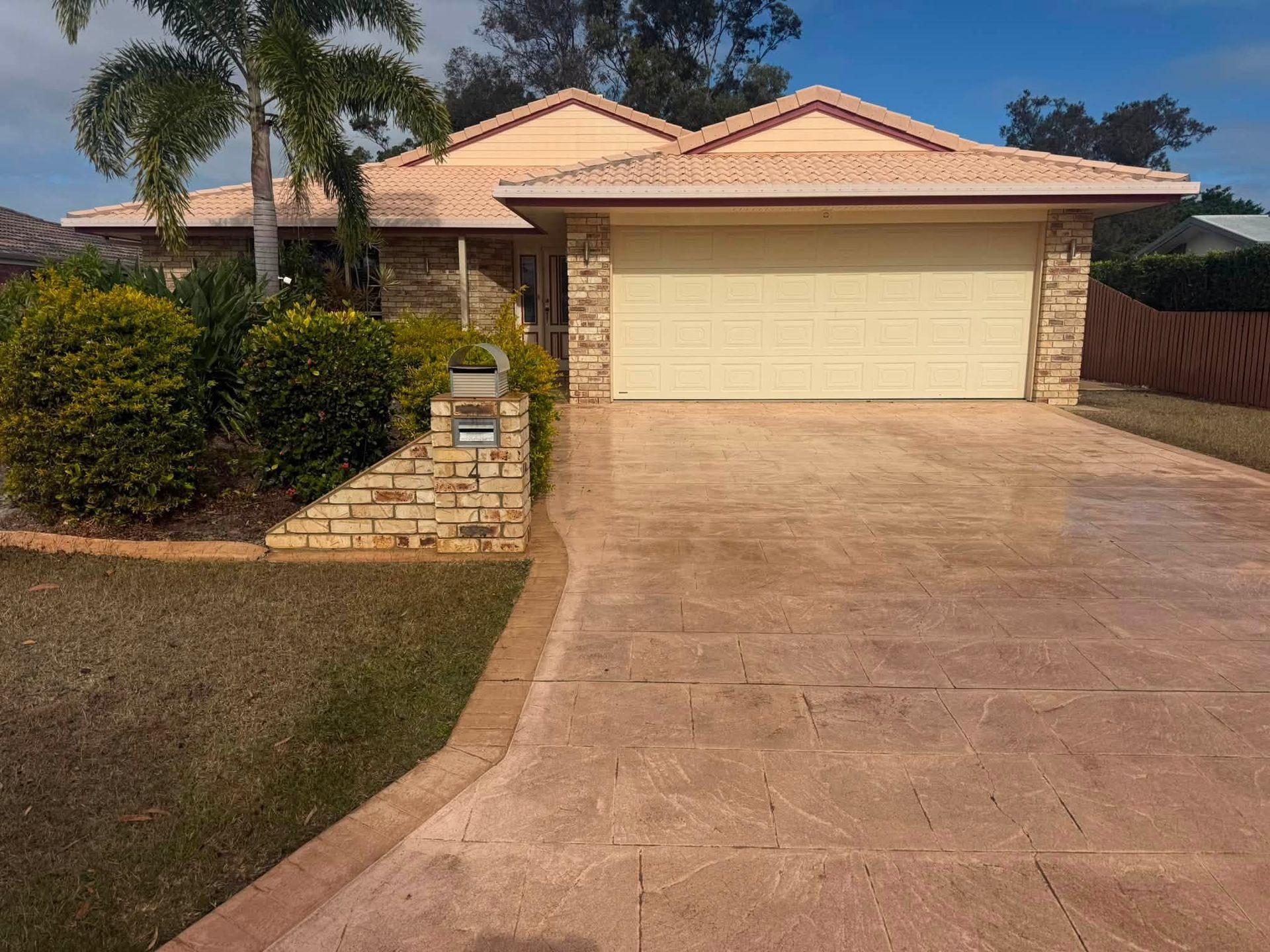 Single-story Suburban House With a Tan Garage, Driveway, and Front Yard Landscaping — CPR Exterior Cleaning in Bargara, QLD