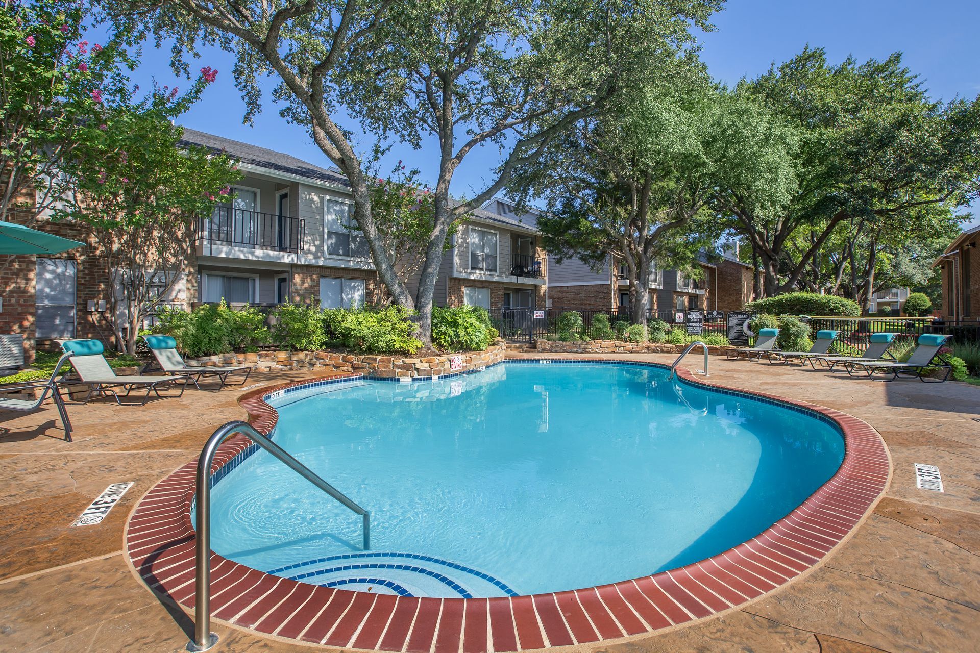 A large swimming pool with stairs leading to it in front of a building.