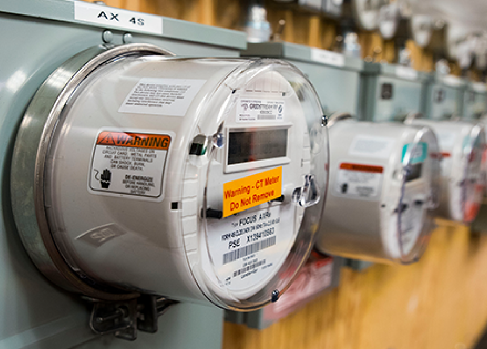 A row of electric meters are lined up on a wall.