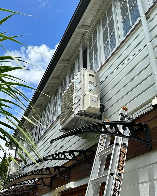 A Person is Standing on a Ladder Next to a Large Air Conditioner  — Eclipse Air Conditioning and Refrigeration In Redlynch, QLD
