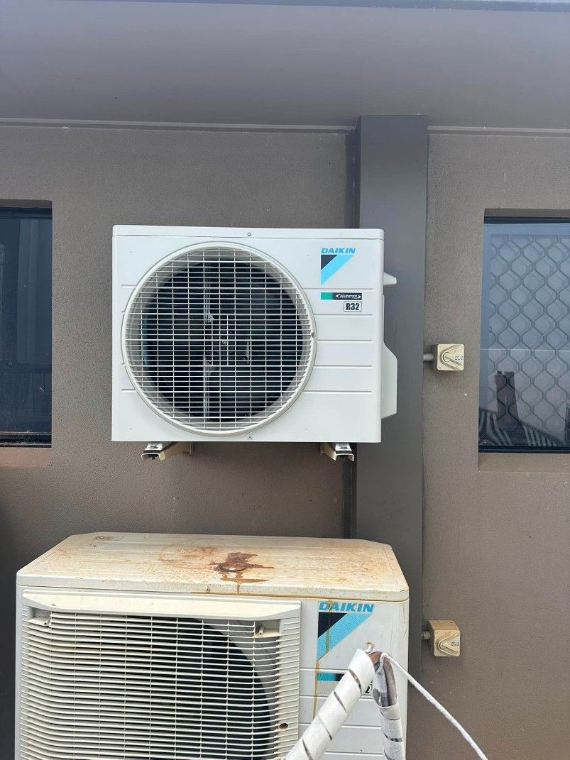 A White Air Conditioner is Mounted on the Side of a Building — Eclipse Air Conditioning and Refrigeration In Smithfield, NSW