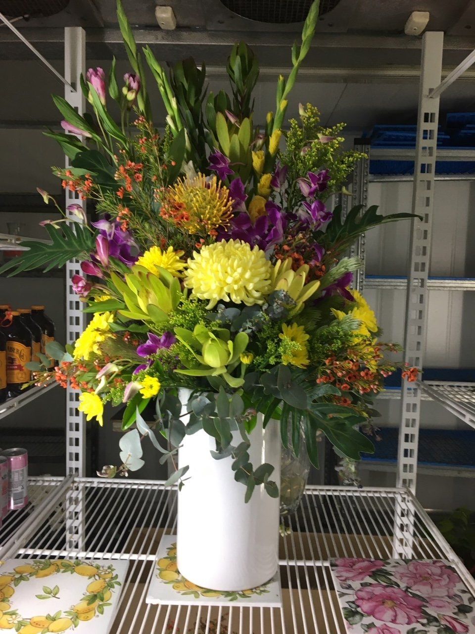 A White Vase Filled with Flowers Is Sitting on A Shelf — Fiori With Love in Ingham, QLD