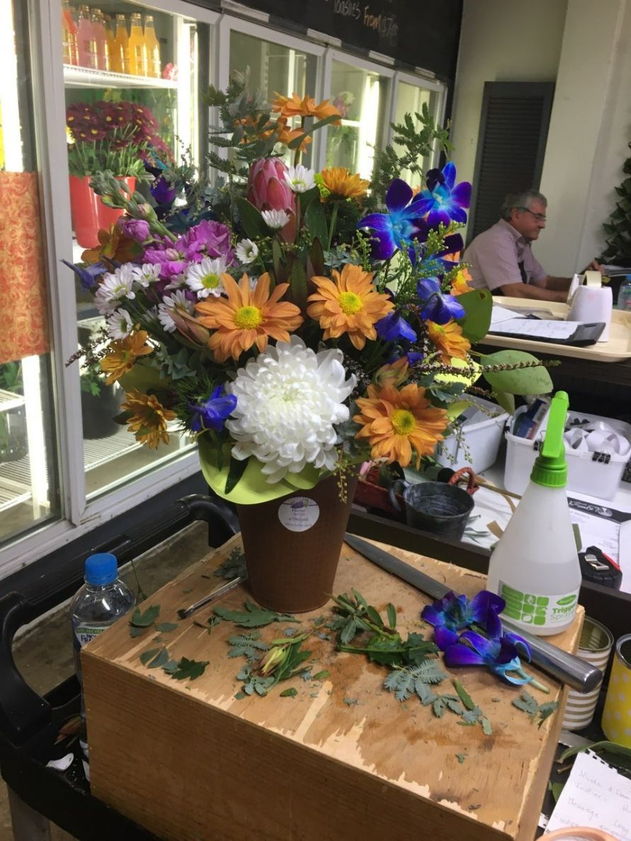 A Vase of Flowers Is Sitting on A Wooden Box on A Table — Fiori With Love in Ingham, QLD