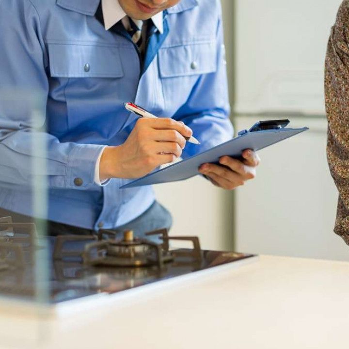 a man is writing on a clipboard in front of a stove .