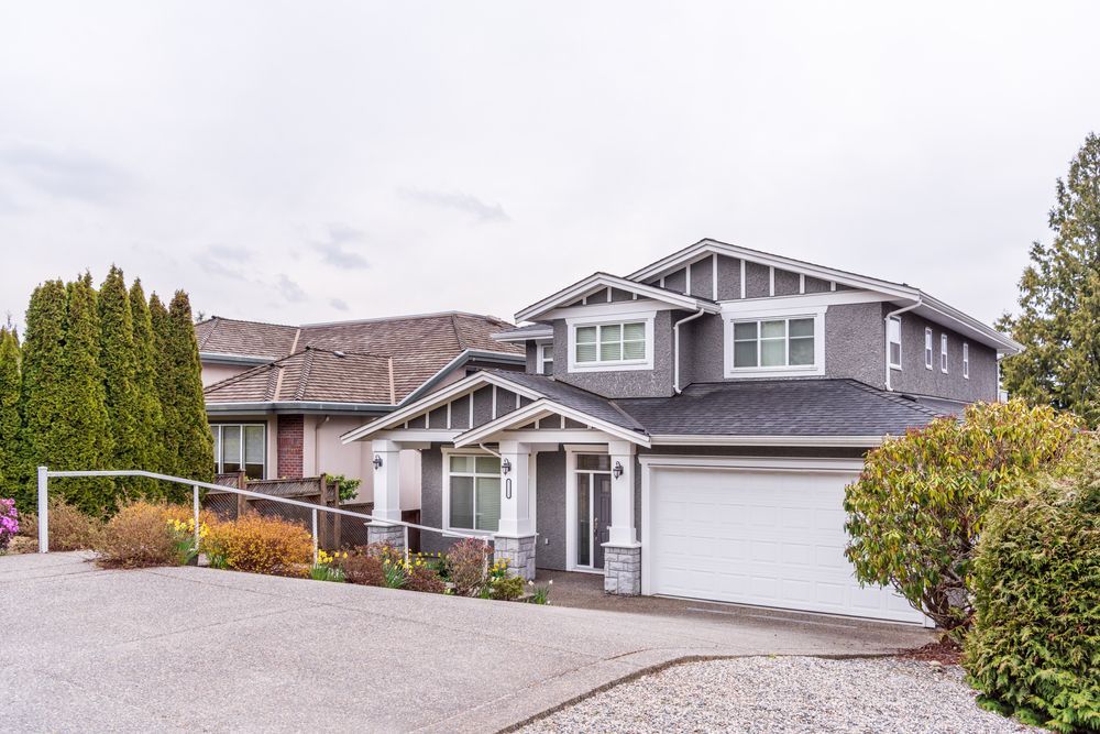 a large house with a white garage door is sitting on top of a hill .