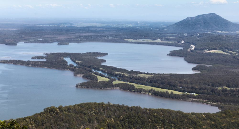 An Aerial View of A Large Body of Water Surrounded by Trees and Mountains — TJL Business Advisors & Accountants in Laurieton, NSW