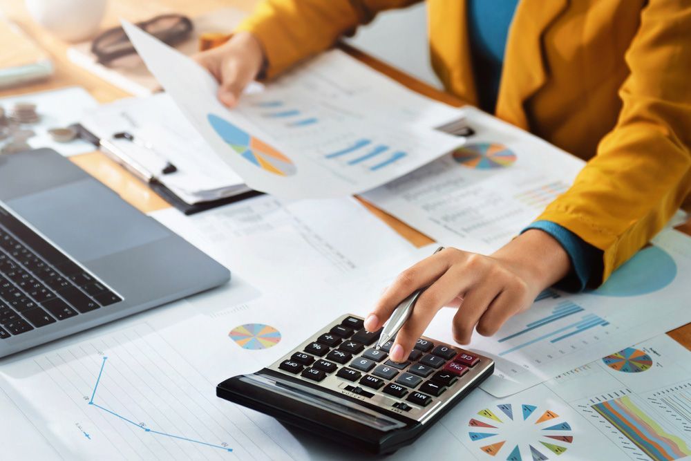 A Person Is Using a Calculator at A Desk While Holding a Piece of Paper — TJL Business Advisors & Accountants in Forster, NSW