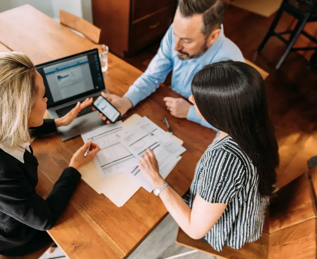 A Man in a Suit and Tie is Sitting at a Table With Two Women — TJL Business Advisors & Accountants in Forster, NSW