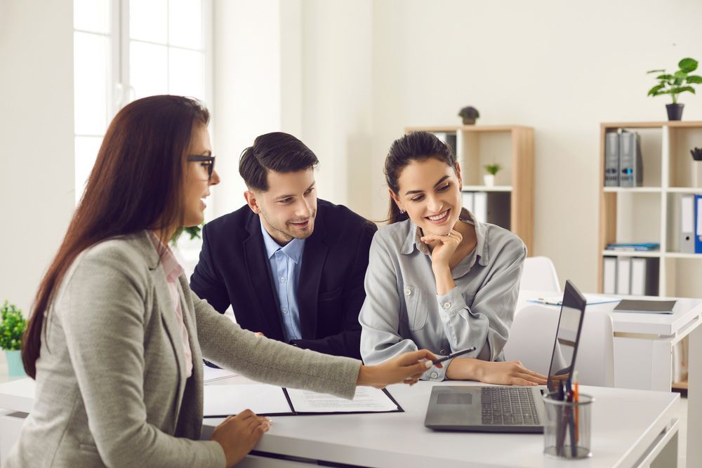 A Man and a Woman Are Sitting at a Table Looking at a Laptop — TJL Business Advisors & Accountants in Forster, NSW