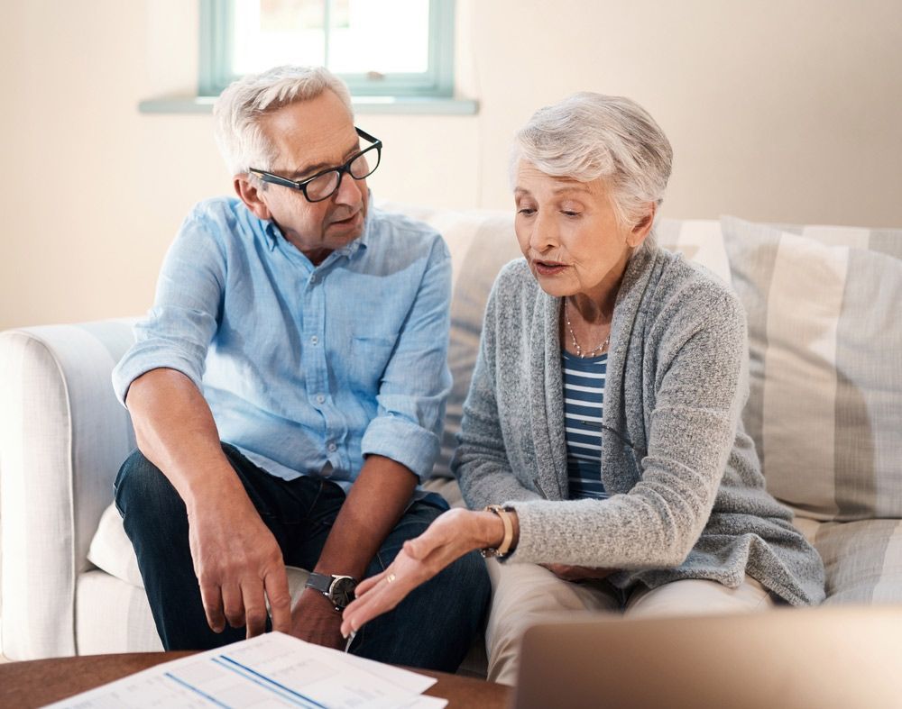 An Elderly Couple is Sitting on a Couch Looking at a Laptop — TJL Business Advisors & Accountants in Forster, NSW