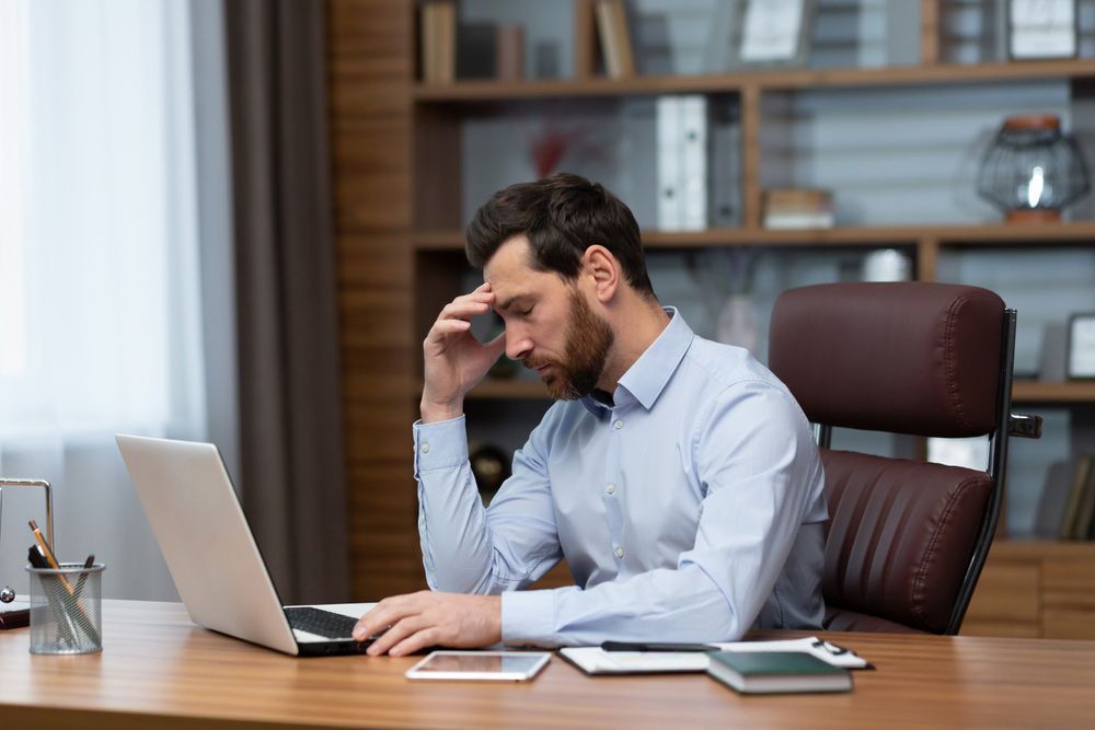 A Man is Sitting at a Desk Using a Laptop Computer — TJL Business Advisors & Accountants in Forster, NSW