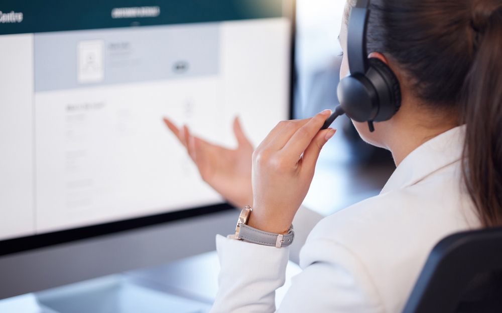 A Woman Wearing a Headset is Sitting in Front of a Computer — TJL Business Advisors & Accountants in Forster, NSW