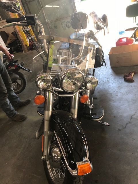 A man is standing next to a black motorcycle in a garage