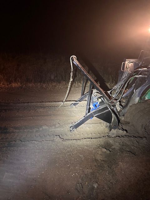 A tractor is sitting in the dirt at night.