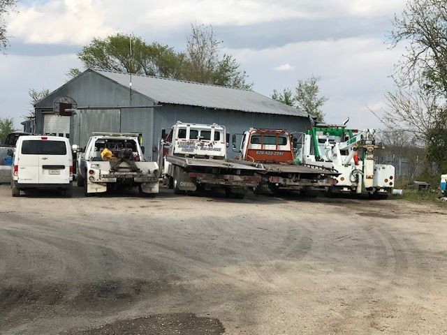 A row of tow trucks are parked in front of a building.