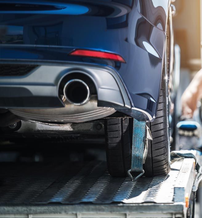 A blue car is being towed by a tow truck.