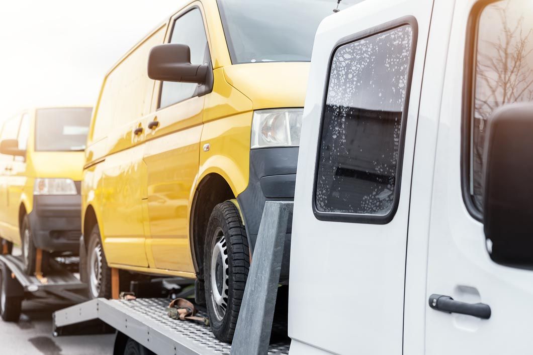 A yellow van is being towed by a tow truck.