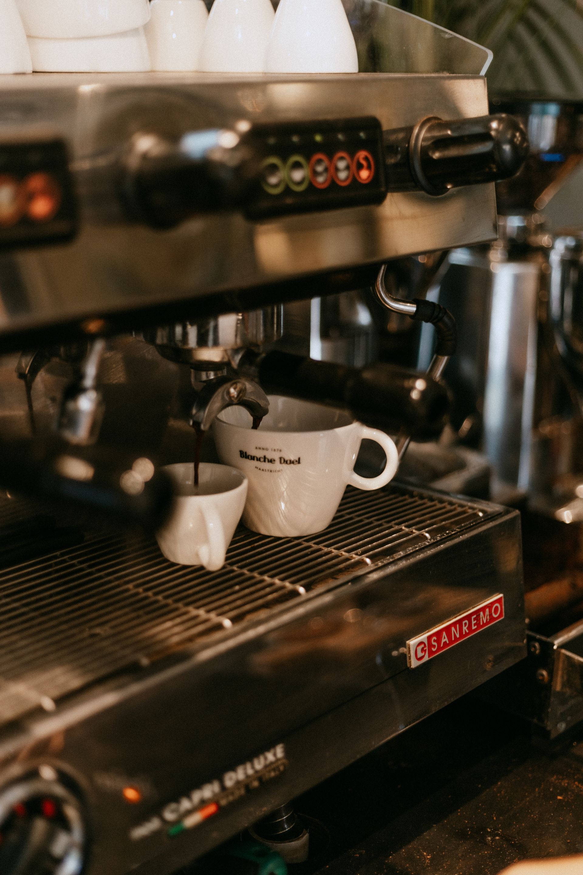 Koffiekopjes op het lekbakje van een espressomachine in een café.