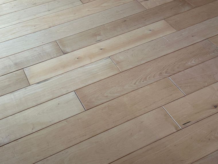 Light wood plank flooring with visible seams and a few darker stained boards